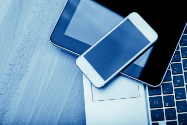Dizüstü bilgisayar ile telefon ve tablet pc ahşap masa, mavi tonda