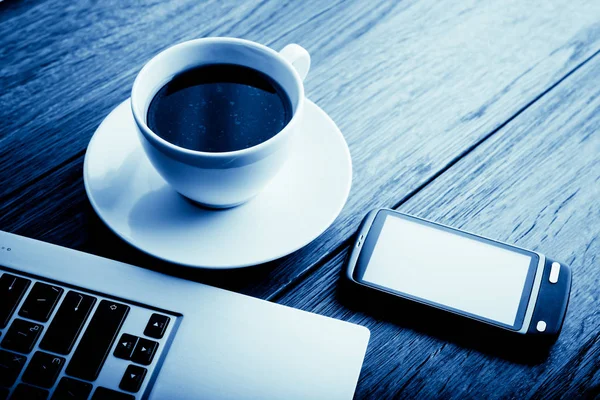 オープン ノート パソコン携帯電話と一杯のコーヒー 木製机の上で事務所職場トーン ブルー — ストック写真