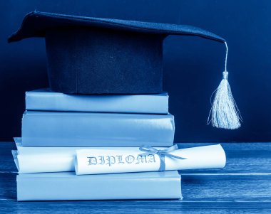 Bir kitap yığını üzerinde kırmızı kurdele ile bağlanmış bir kolej ve mezuniyet kaydırma 