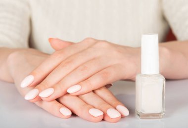 woman's hands with white nail varnish bottles. Nails care clipart