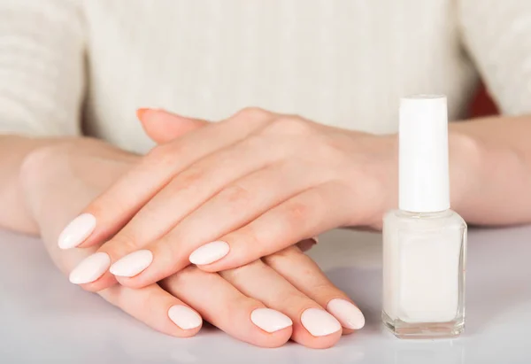 woman's hands with white nail varnish bottles. Nails care