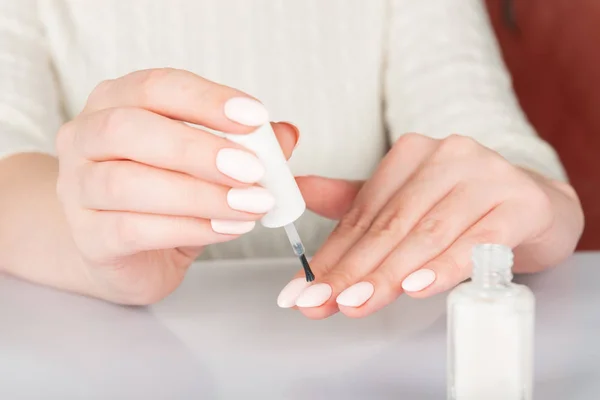 woman\'s hands with white nail varnish bottles. Nails care