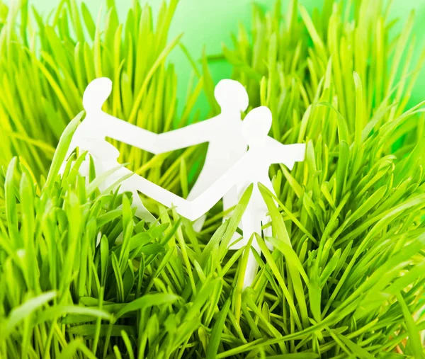 Paper people on green grass on bright background