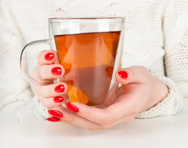 女性の手は 熱いお茶の透明カップを保持しています 美しい赤のマニキュア — ストック写真