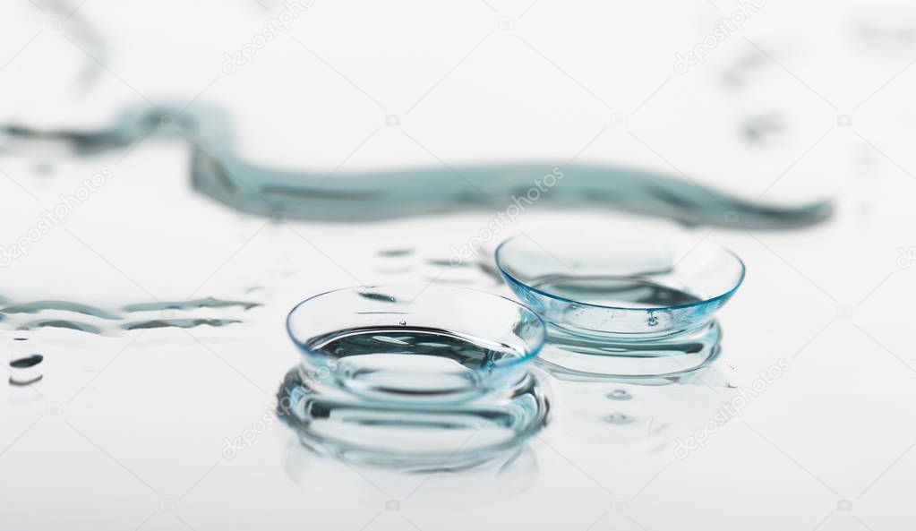 Two contact lenses with reflection on glass table