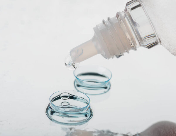 Bottle with contact lenses solution and case on table, closeup view