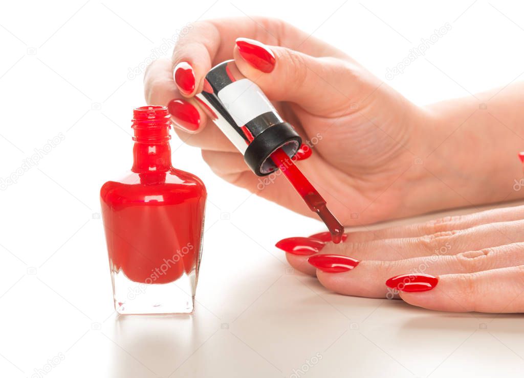 Female hand with red nail polish bottle