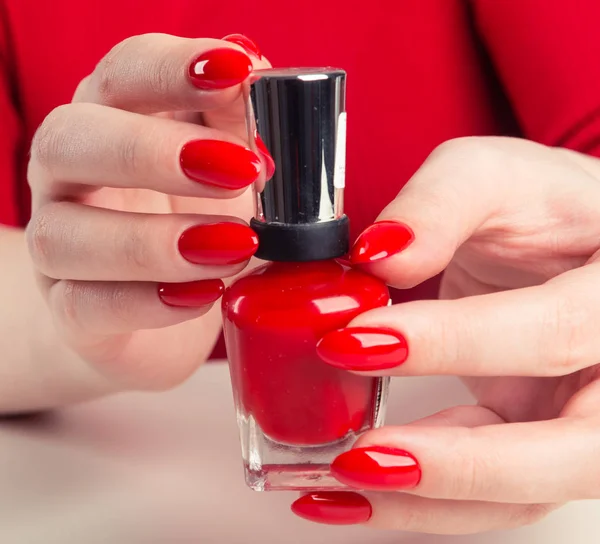 Female hand with red nail polish bottle