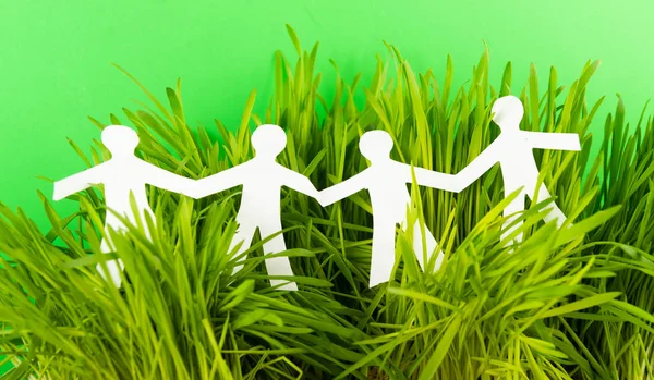 Paper people on green grass on bright background