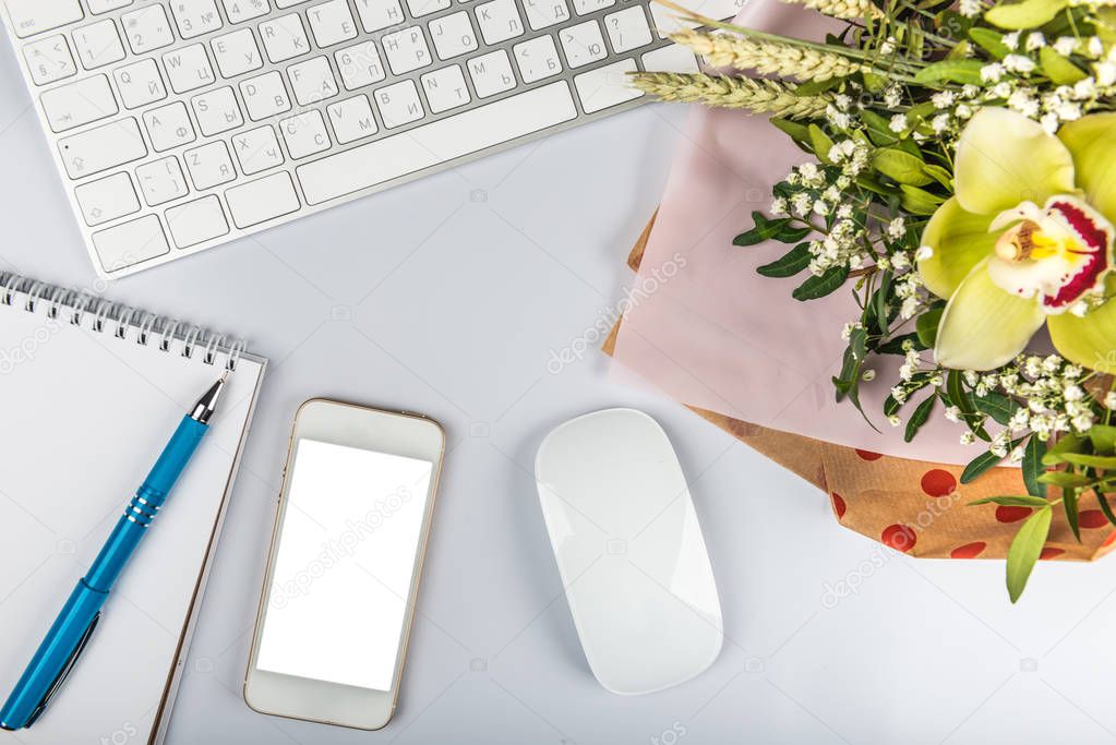 White office desk table with keyboard, phone, writing supplies a