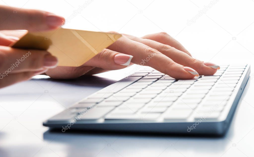 Hands holding a credit card and using laptop computer for online