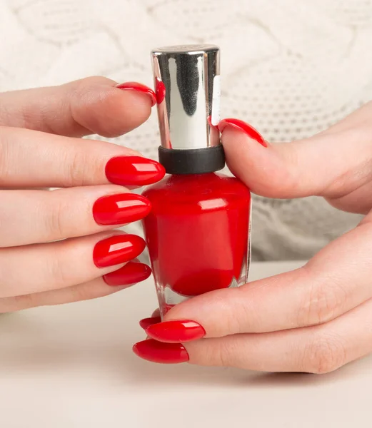 Female hand with red nail polish bottl