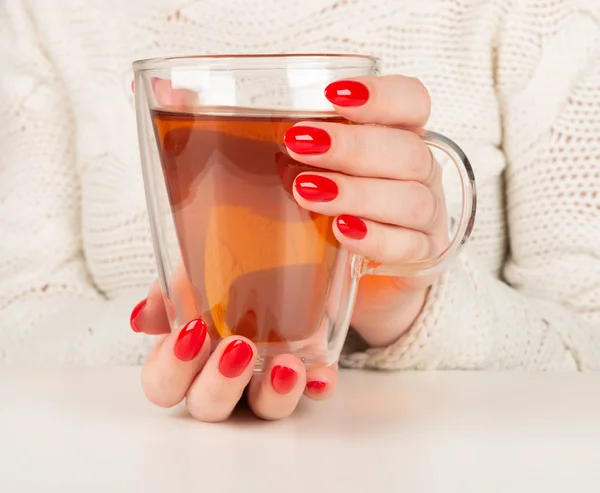 Kobiece ręce trzymając przezroczystą filiżankę gorącej herbaty — Zdjęcie stockowe