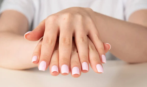 Mano femenina con diseño de uñas rosa claro — Foto de Stock