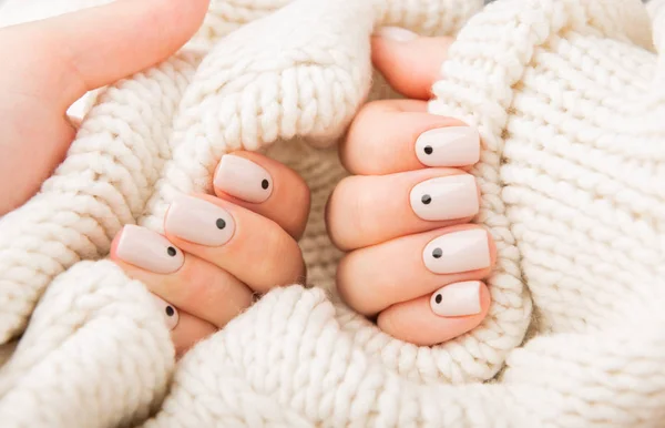 Unhas bege com pontos segurando material de lã de malha — Fotografia de Stock