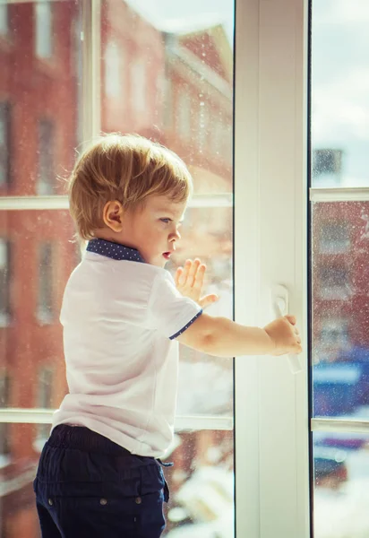 Kleine jongen en raam — Stockfoto