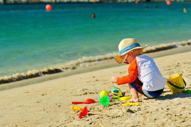 Sahilde plaj oyuncakları ile oynarken iki yaşında bir yürümeye başlayan çocuk 