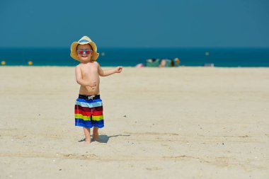 Plajda çalışan güneş şapkalı iki yaşında yürümeye başlayan çocuk 