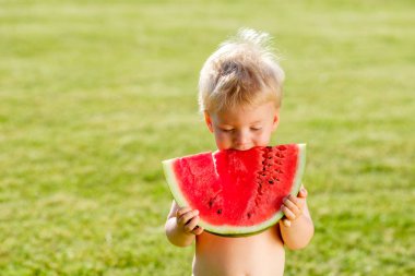 Yürümeye başlayan çocuk açık havada portresi. Karpuz dilimi bahçede yemek bir yaşında bir bebek çocuk ile kırsal manzara. 