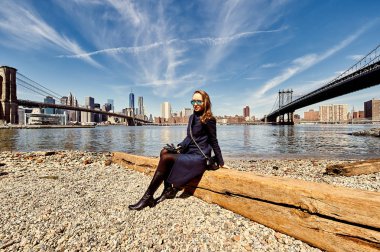 Brooklyn Köprüsü ve New York City'deki Manhattan Köprüsü arasında kıyısında oturan kadın