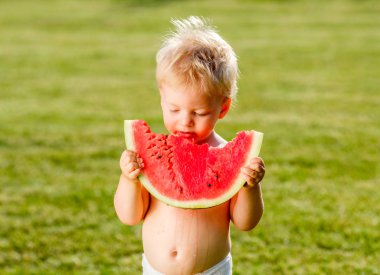 Yürümeye başlayan çocuk açık havada portresi. Karpuz dilimi bahçede yemek bir yaşında bir bebek çocuk ile kırsal sahne. Mutlu bir çocukluk kirli pis yüzü.