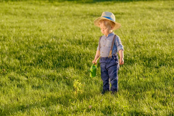 Yürümeye başlayan çocuk açık havada portresi. Hasır şapka sulama olabilir kullanarak bir yaşında bir bebek çocuk ile kırsal manzara