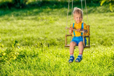 Açık havada sallanan yürümeye başlayan çocuk portresi. Erkek salıncak bir yaşında bebek ile kırsal sahne. Sağlıklı okul öncesi çocuklar yaz etkinliği. Dışarıda oynayan çocuk. 