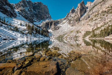 Zümrüt Gölü ve sonbaharda etrafındaki kayalar ve dağlarla yansıması. Colorado, ABD 'deki Rocky Dağı Ulusal Parkı. 