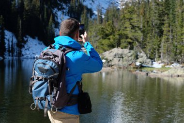 Uzun yürüyüşe çıkan kimse turist ile smartphone Bear Lake sonbahar Rocky Dağı Milli Parkı'fotoğrafta sırt çantası ile. Colorado, ABD. 