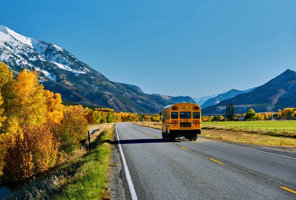 School bus on highway in Colorado Rocky Mountains at autumn, USA. Mount Sopris landscape.