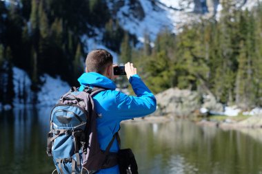 Uzun yürüyüşe çıkan kimse turist ile smartphone Bear Lake sonbahar Rocky Dağı Milli Parkı'fotoğrafta sırt çantası ile. Colorado, ABD. 