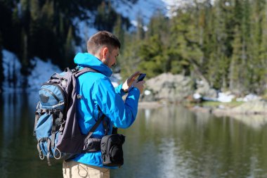 Uzun yürüyüşe çıkan kimse turist ile smartphone Bear Lake sonbahar Rocky Dağı Milli Parkı'fotoğrafta sırt çantası ile. Colorado, ABD. 