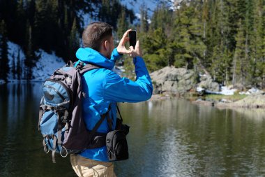 Uzun yürüyüşe çıkan kimse turist ile smartphone Bear Lake sonbahar Rocky Dağı Milli Parkı'fotoğrafta sırt çantası ile. Colorado, ABD. 