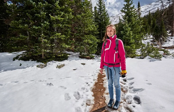ロッキー山国立公園 コロラド州 米国の雪に覆われた道でハイキングのバックパックで女性観光客 — ストック写真