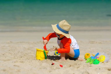 Sahilde plaj oyuncakları ile oynarken iki yaşında bir yürümeye başlayan çocuk 