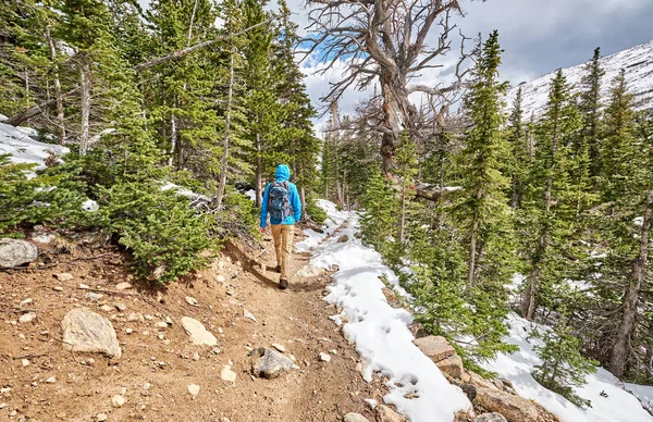 ロッキー山国立公園 コロラド州 米国の雪に覆われた道でハイキングのバックパックと男性の観光客 — ストック写真