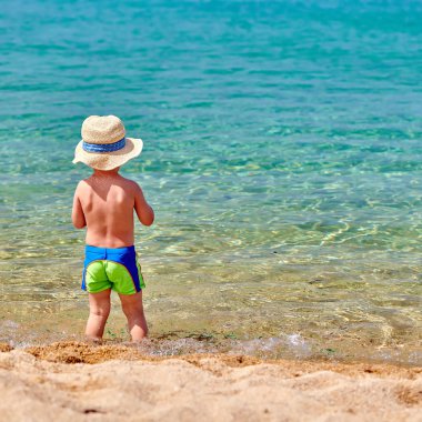 Kum plajındaki iki yaşında bir yürümeye başlayan çocuk 