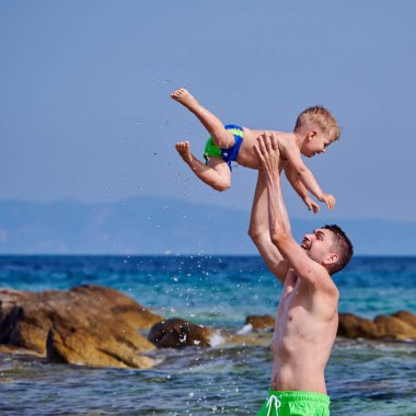 İki yaşındaki yürümeye başlayan çocuk babası ile sahilde 