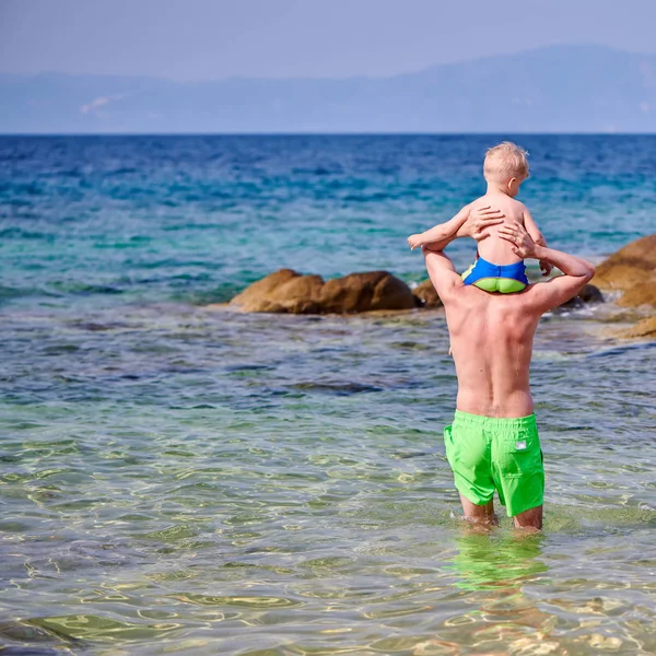 两岁的幼儿男孩在海滩上站在父亲的肩膀上 — 图库照片