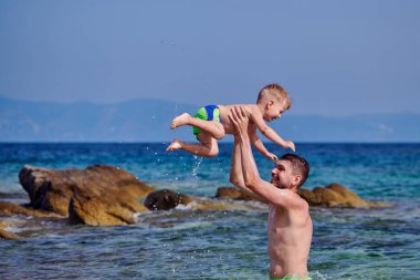 İki yaşındaki yürümeye başlayan çocuk babası ile sahilde 