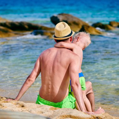 İki yaşındaki yürümeye başlayan çocuk babası ile sahilde 