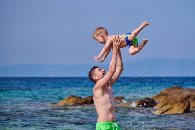 İki yaşındaki yürümeye başlayan çocuk babası ile sahilde 