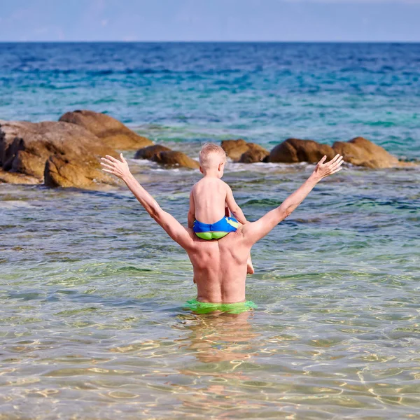 Plajda babasının omuzlarında iki yaşında bir yürümeye başlayan çocuk