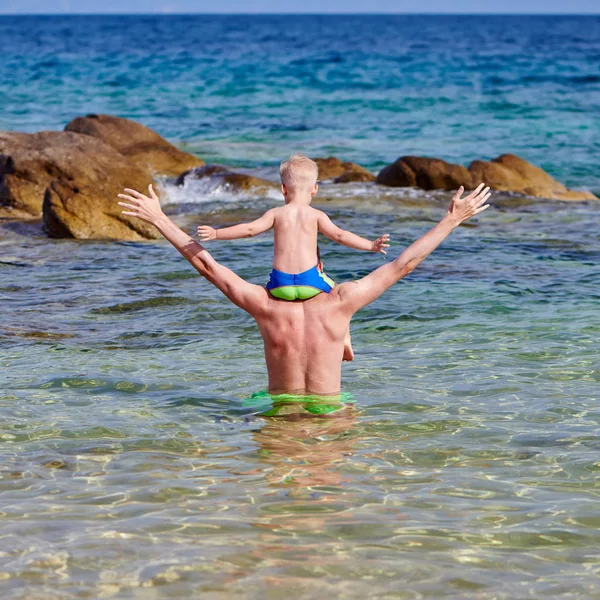 Plajda babasının omuzlarında yürümeye başlayan çocuk — Stok fotoğraf