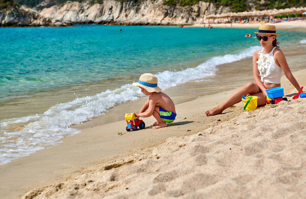 Toddler boy on beach with mother