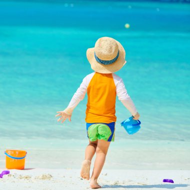 Üç yaşında bir çocuk sahilde oynuyor.