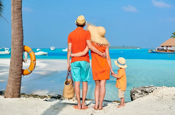 Familj av tre på stranden under palm tree — Stockfoto