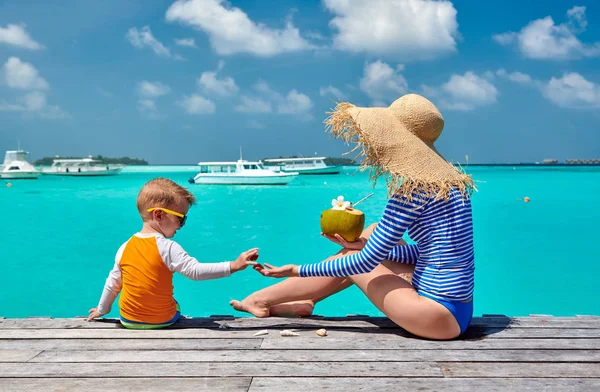 Toddler boy with mother sitting on wooden jetty — Stock Photo, Image