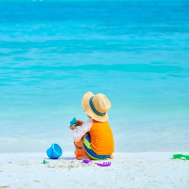 Üç yaşında bir çocuk sahilde oynuyor.