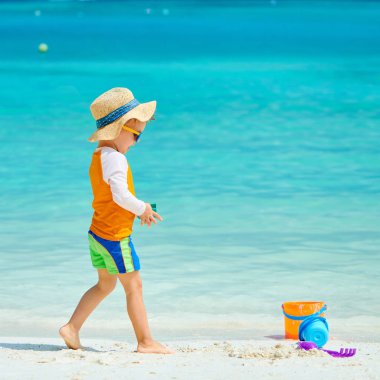 Üç yaşında bir çocuk sahilde oynuyor.